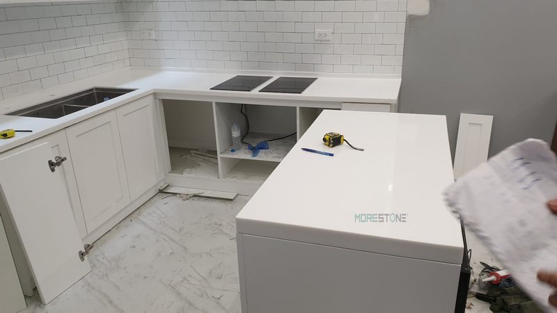 Tủ bếp được ốp bằng đá nhân tạo màu trắng có ưu điểm uốn nắn vượt trội không để lại mấu nối một mạch liền nhau mang lại tính thẩm mỹ cao